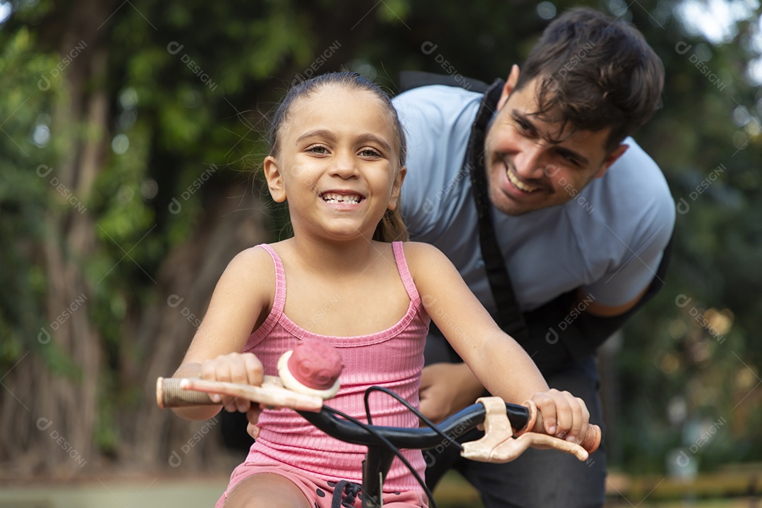 Menina feliz andando de bicicleta com seu pai