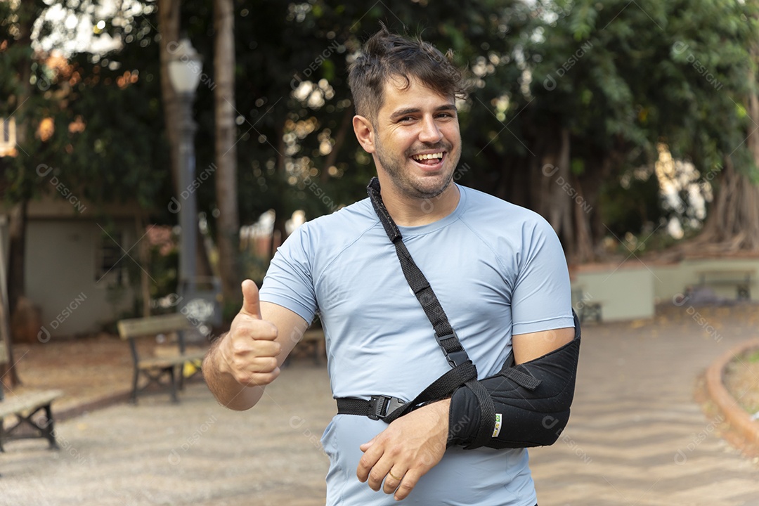 Homem feliz com gesto de ok e braço na tipoia