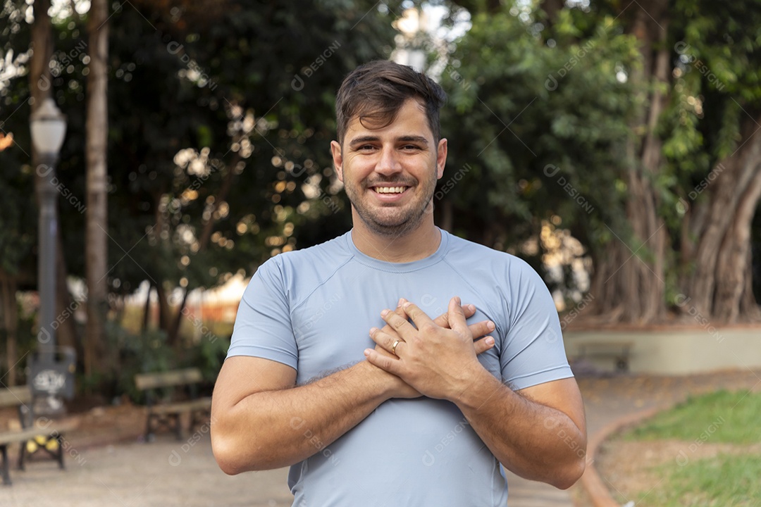 Homem sorrindo com mãos no peito