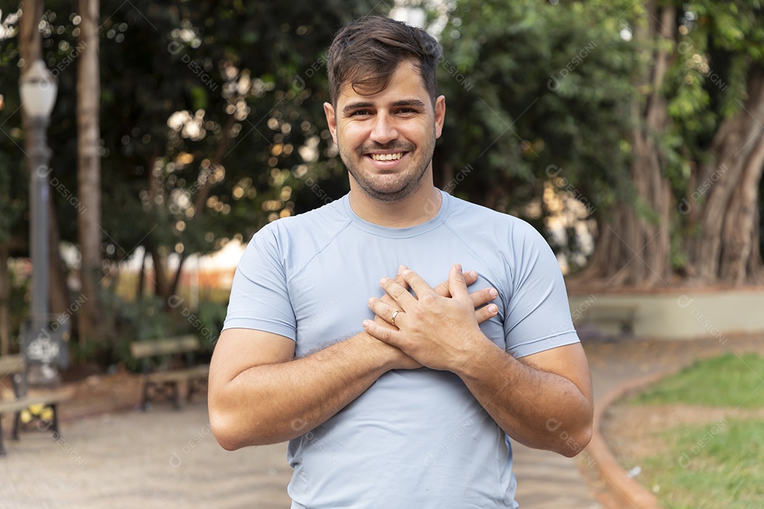 Homem sorrindo com mãos no peito