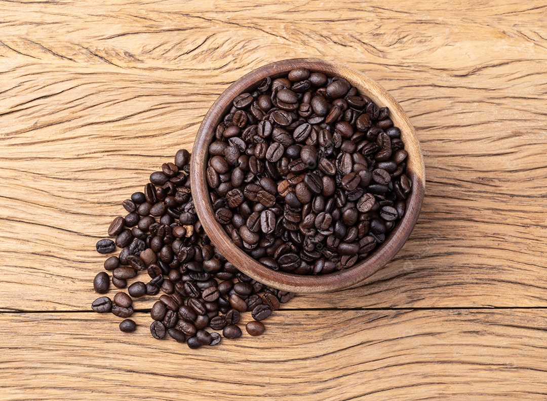 Grãos de café em uma tigela sobre a mesa de madeira