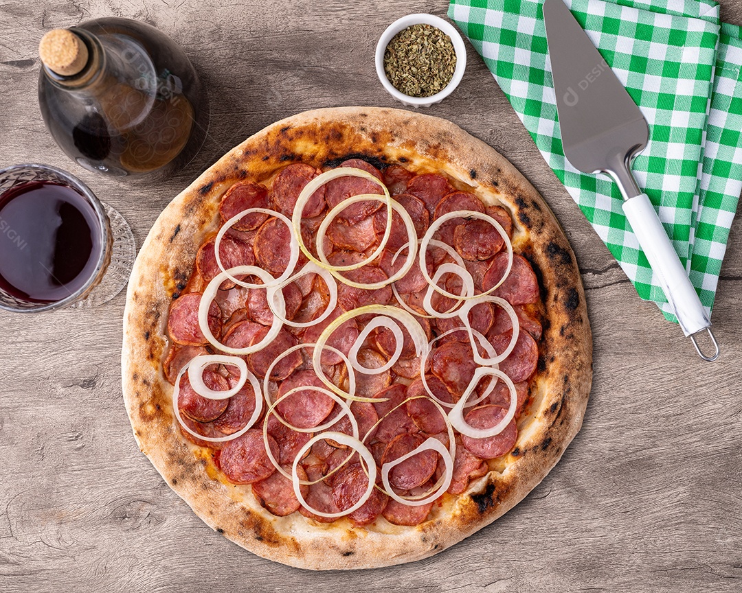 Pizza de calabresa acebolada com uma taça de vinho