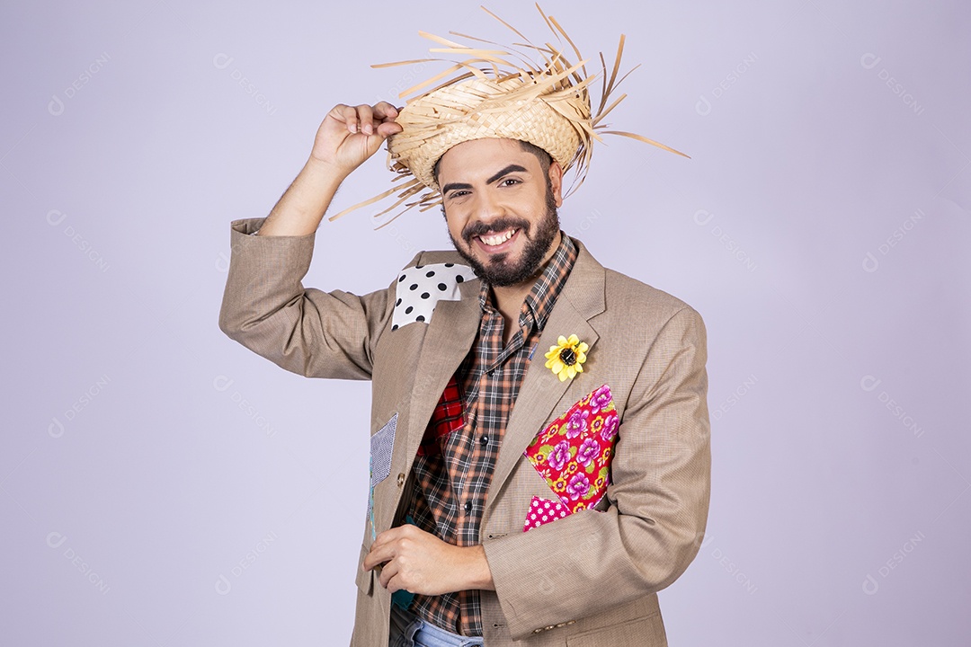 Rapaz a caráter de festa junina segurando chapéu na cabeça