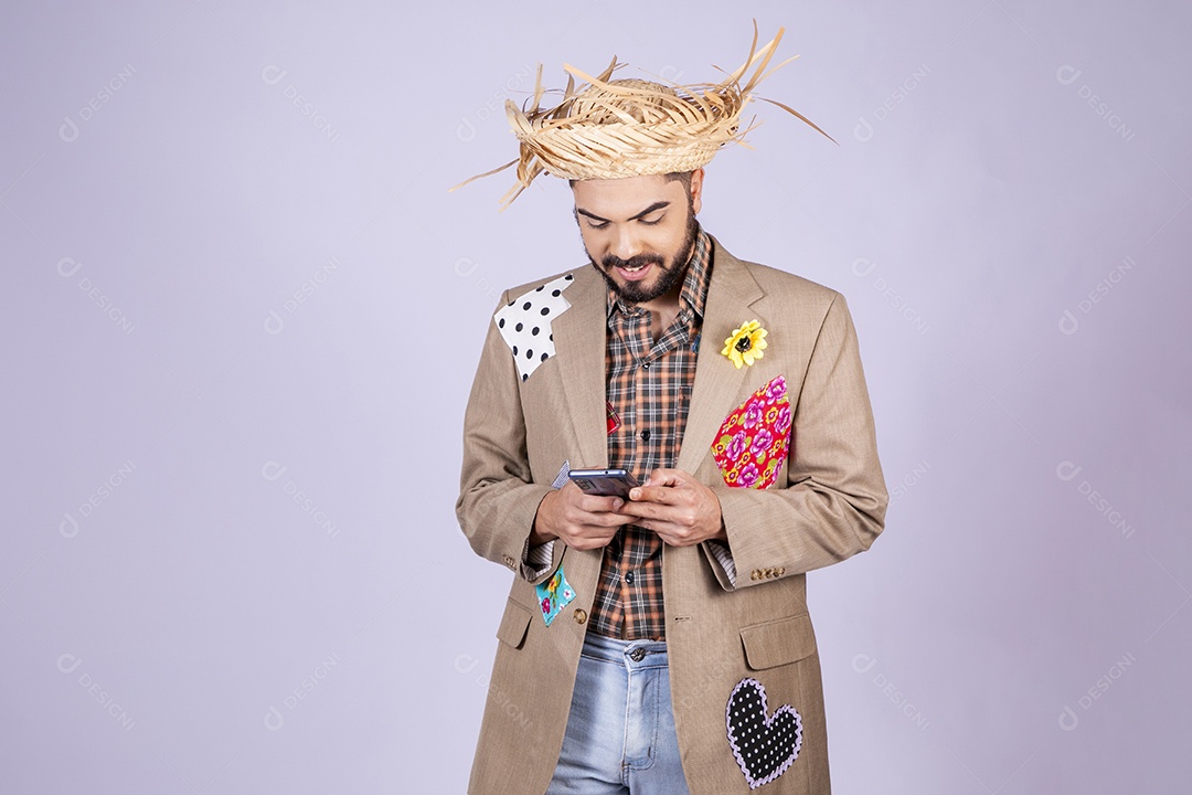 Jovem rapaz trajado para festa junina sorrindo com celular na mão