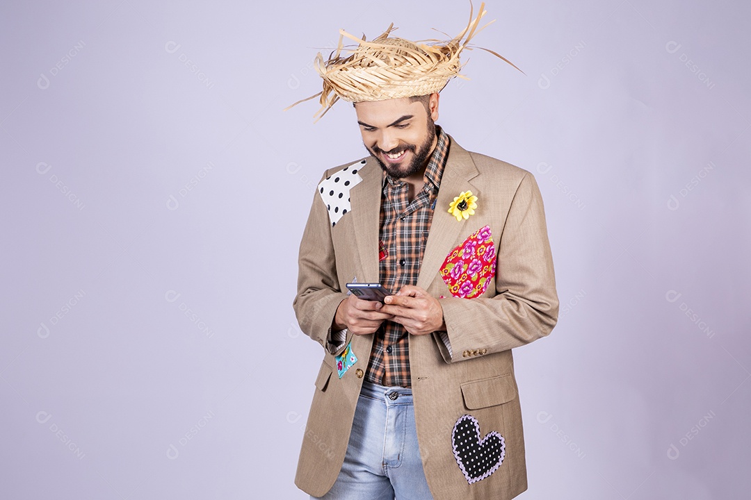 Jovem rapaz trajado para festa junina sorrindo com celular na mão