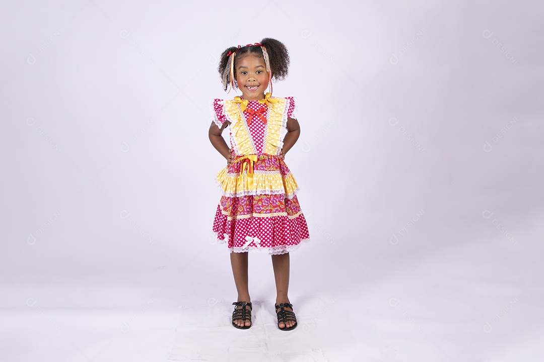 Linda garotinha trajada para festa junina com mãos na cintura e sorrindo