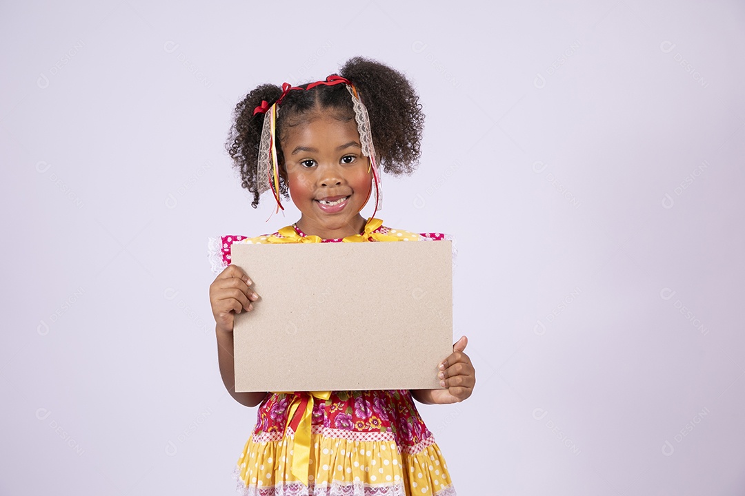 Quadrilheira mirim com plaquinha na mão e sorrindo