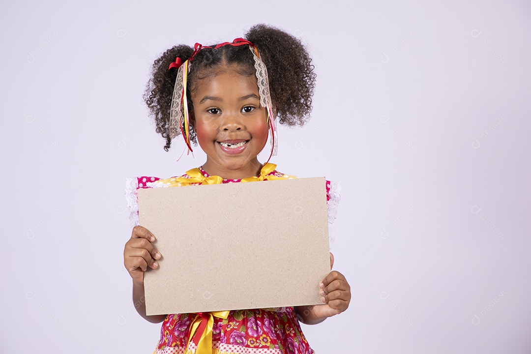 Quadrilheira mirim com plaquinha na mão e sorrindo