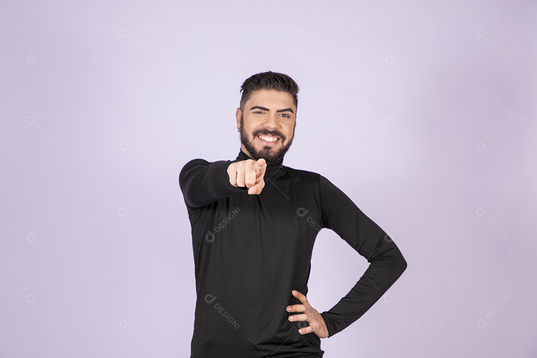 Homem apontando para frente e sorrindo com mãos na cintura