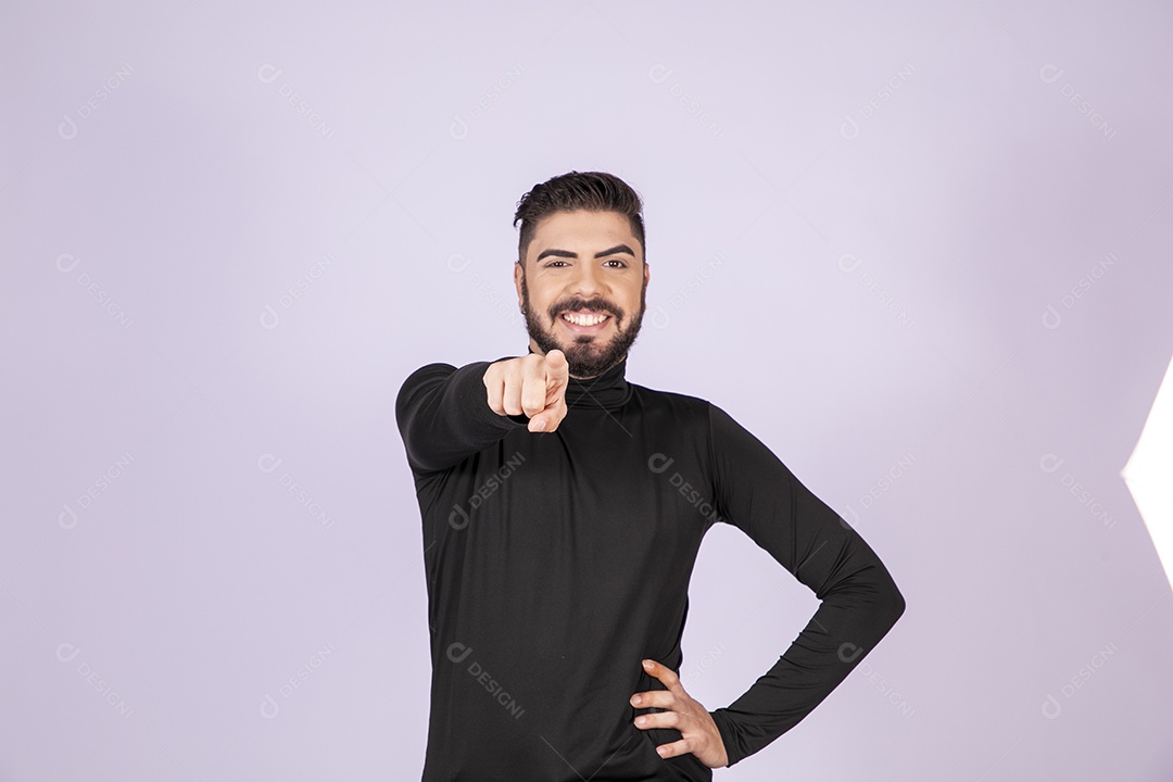 Homem apontando para frente e sorrindo com mãos na cintura