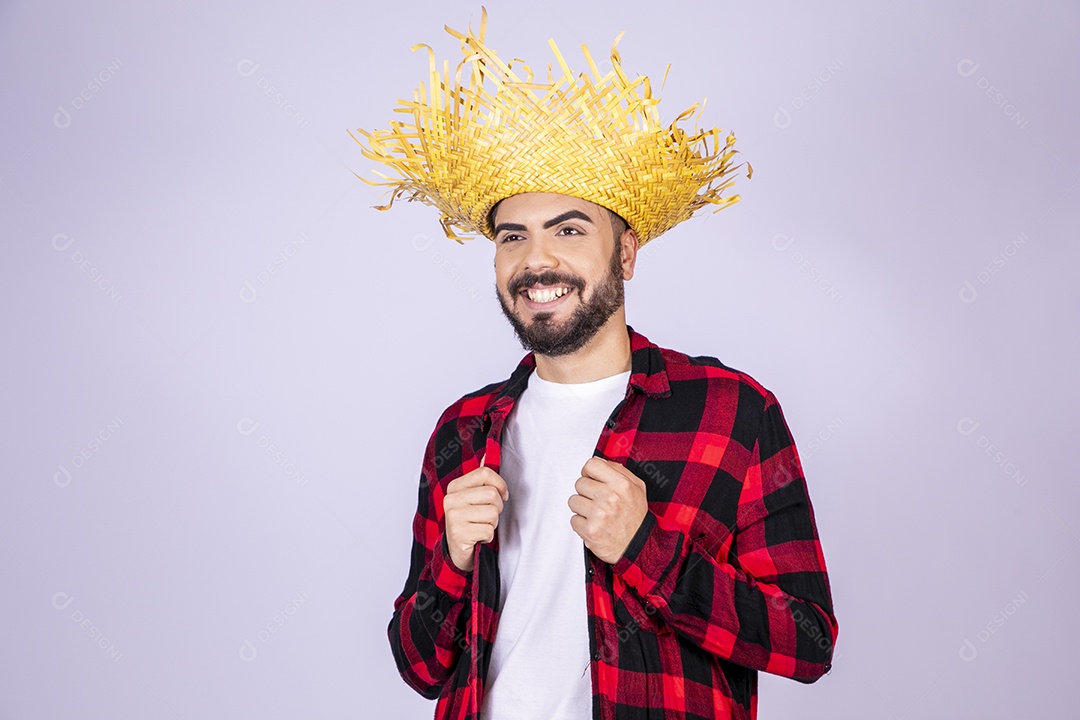 Jovem de xadrez com chapéu de palha sorrindo para festa junina