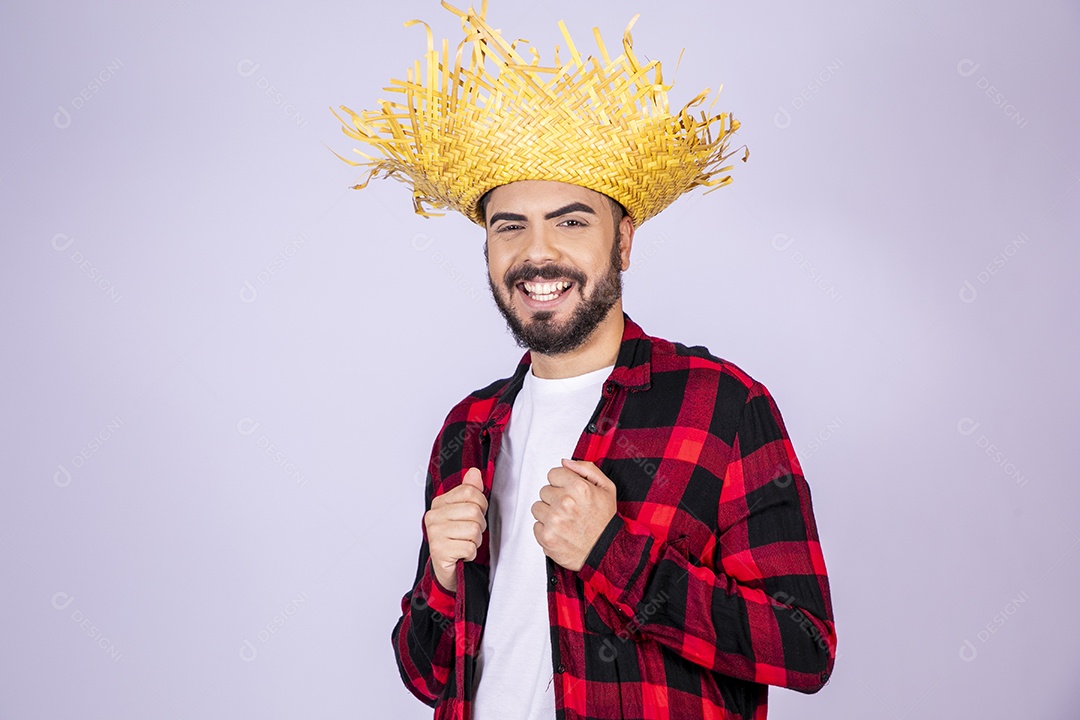 Jovem de xadrez com chapéu de palha sorrindo ajeitando roupa