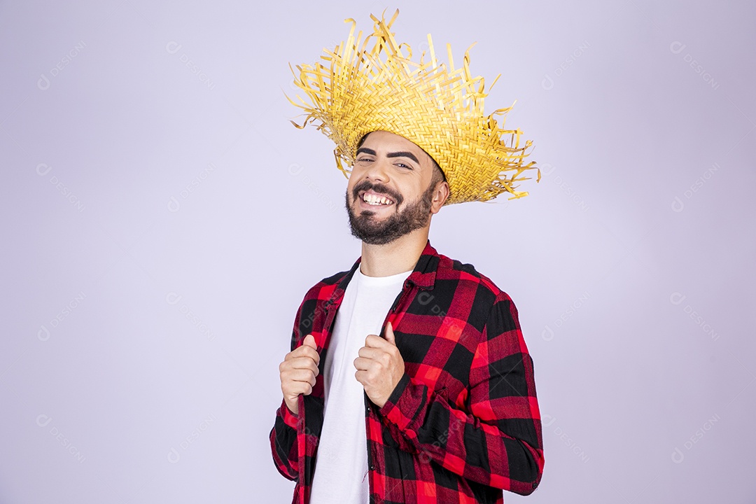 Jovem de xadrez com chapéu de palha sorrindo ajeitando roupa