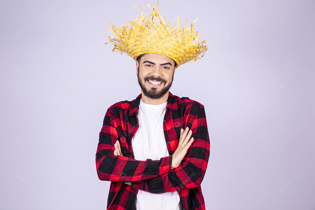 Jovem de xadrez com chapéu de palha sorrindo com braço cruzado