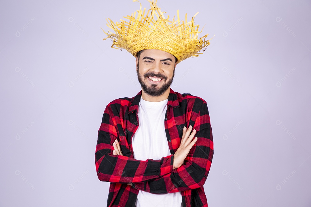 Jovem de xadrez com chapéu de palha sorrindo com braço cruzado