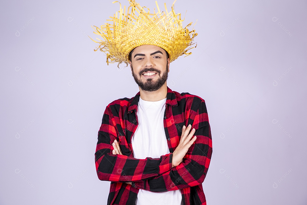 Jovem de xadrez com chapéu de palha sorrindo com braço cruzado