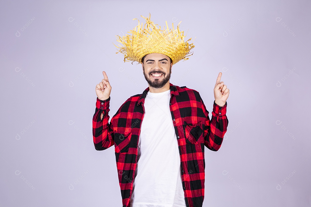 Jovem de xadrez com chapéu de palha sorrindo apontando para cima