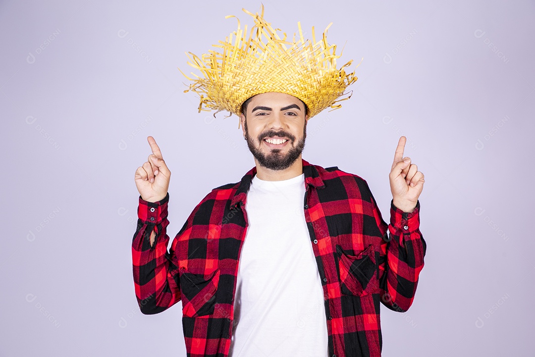 Jovem de xadrez com chapéu de palha sorrindo para festa junina