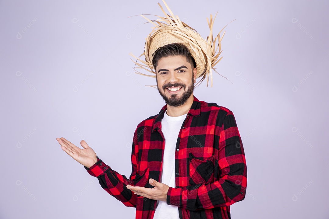 Jovem de xadrez com chapéu de palha sorrindo apontando para o lado