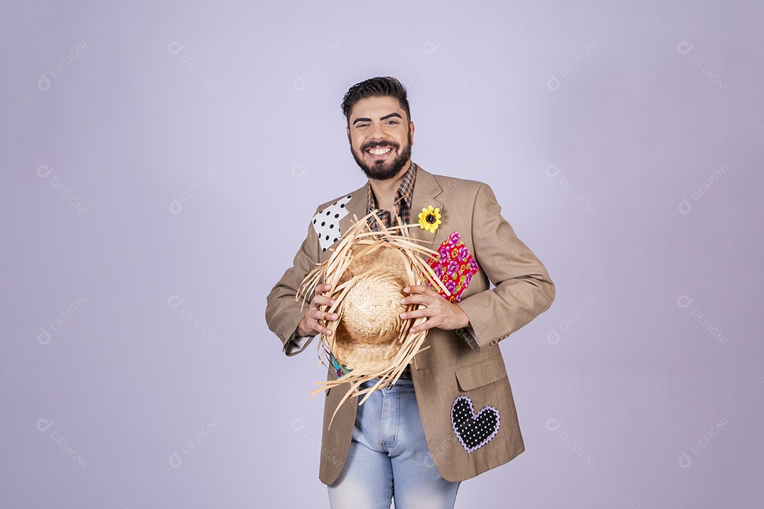 Jovem quadrilheiro animado para festa junina com chapéu nas mãos