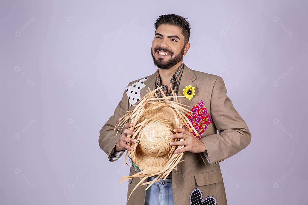 Jovem quadrilheiro animado para festa junina com chapéu nas mãos