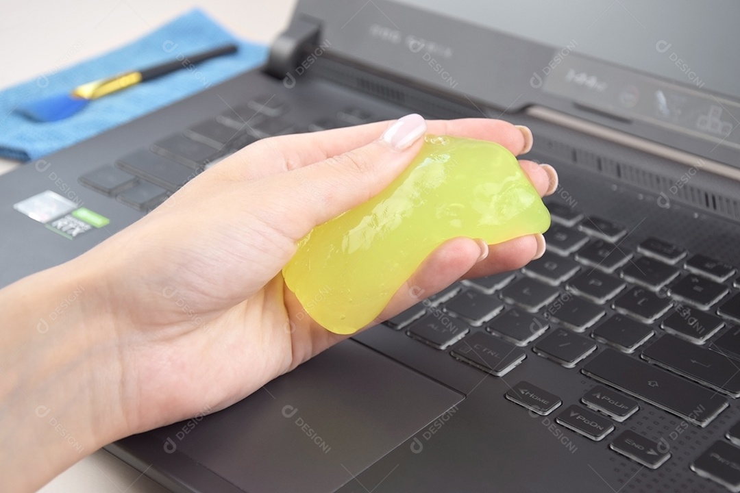 Mão segurando gel de limpeza para teclado
