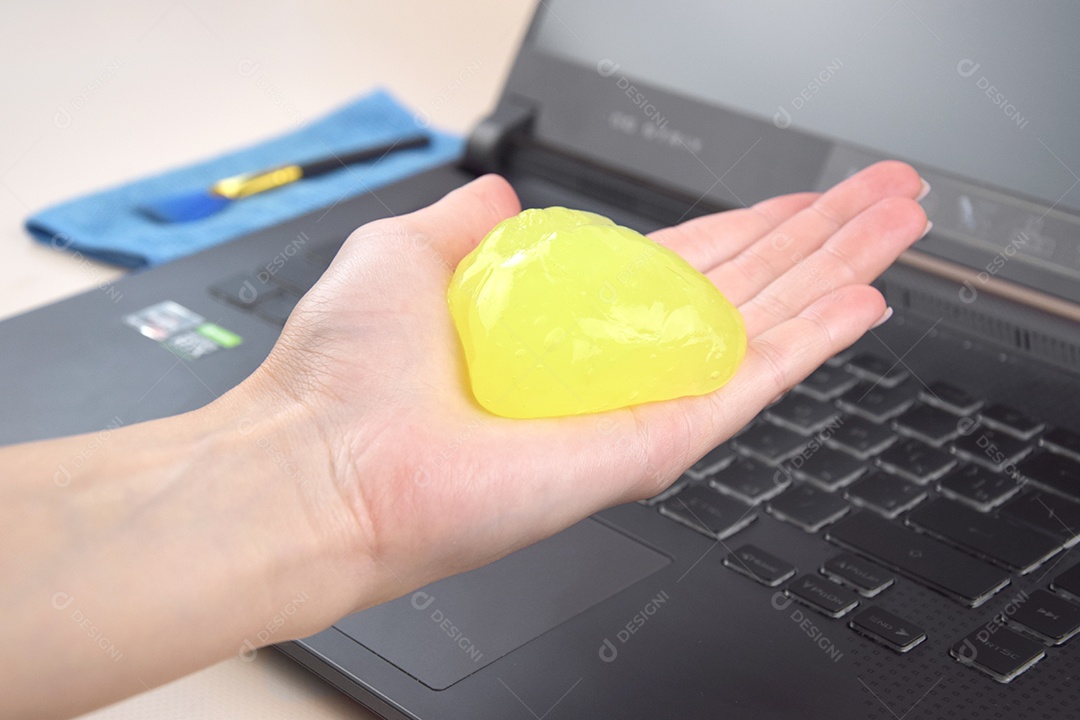 Mão segurando gel de limpeza para teclado