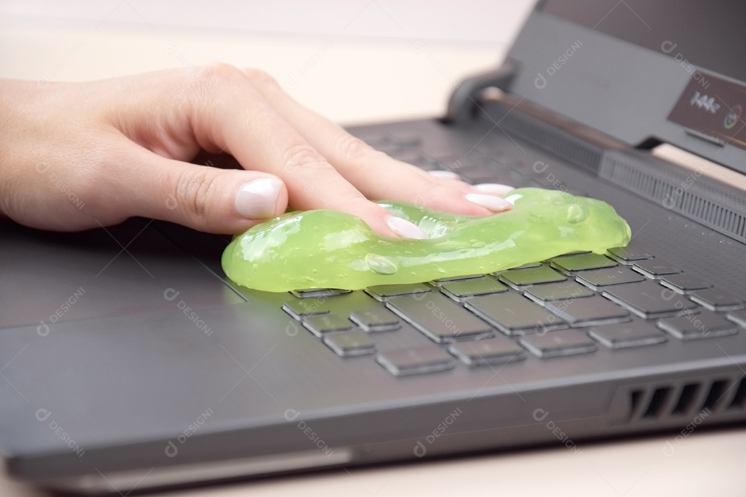 Mão limpando teclado com gel de limpeza verde