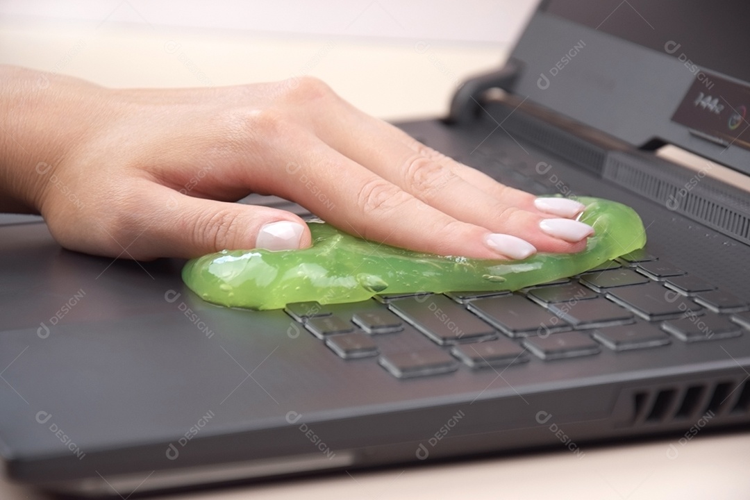 Mão limpando teclado com gel de limpeza verde