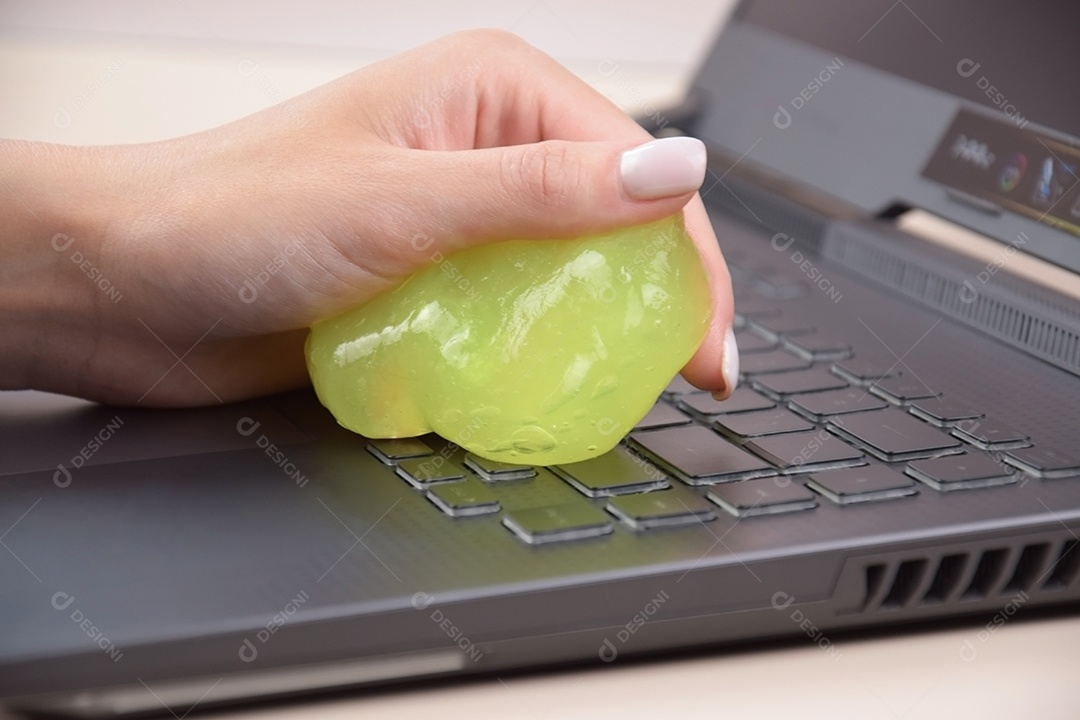 Mão segurando gel de limpeza para teclado