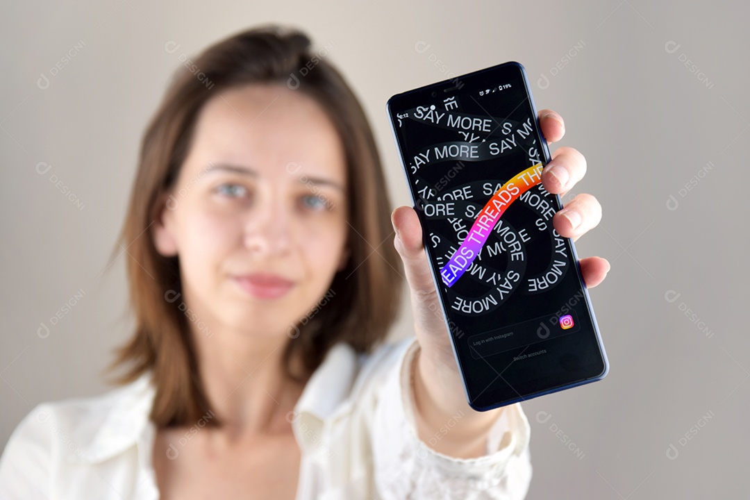 Mulher segurando celular com aplicativo Threads