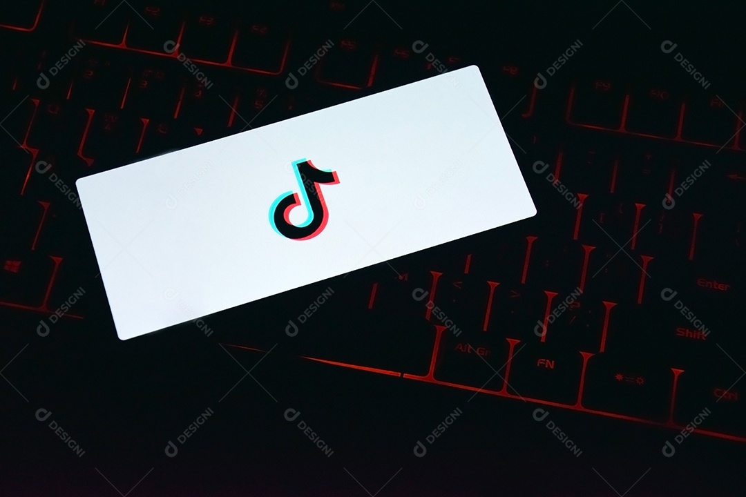 Celular com aplicativo tik tok sobre fundo de teclado vermelho