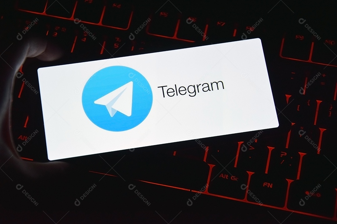 Mão segurando celular aberto com aplicativo telegram