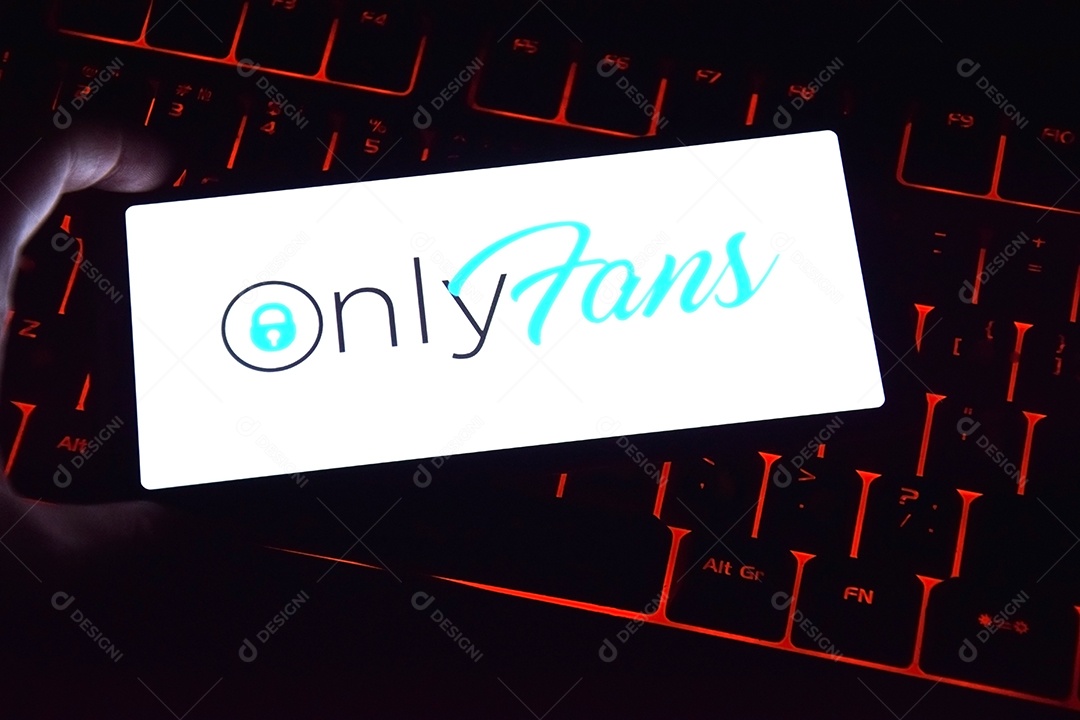 Mão segurando celular sobre fundo de teclado com aplicativo only fans