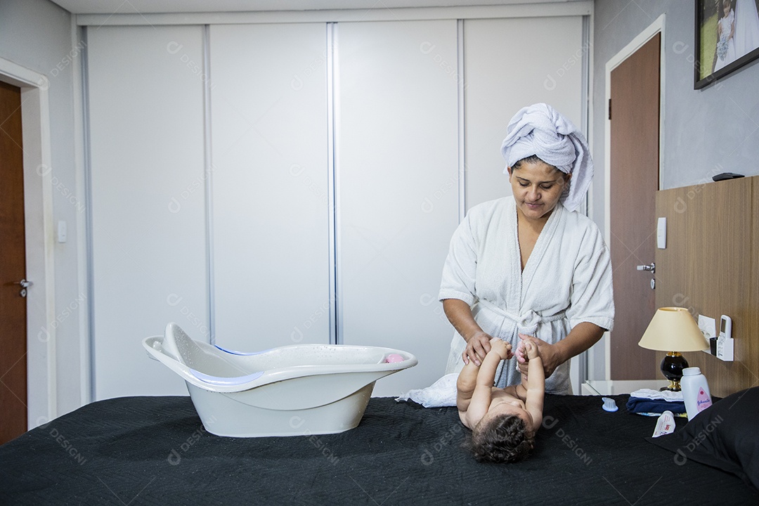 Banheira encima da cama e mãe cuidando do seu bebê