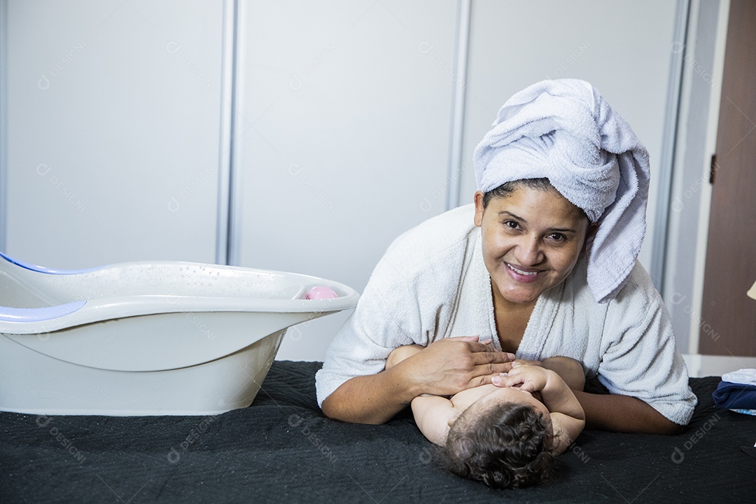 Mãe sorrindo  com seu bebê na cama