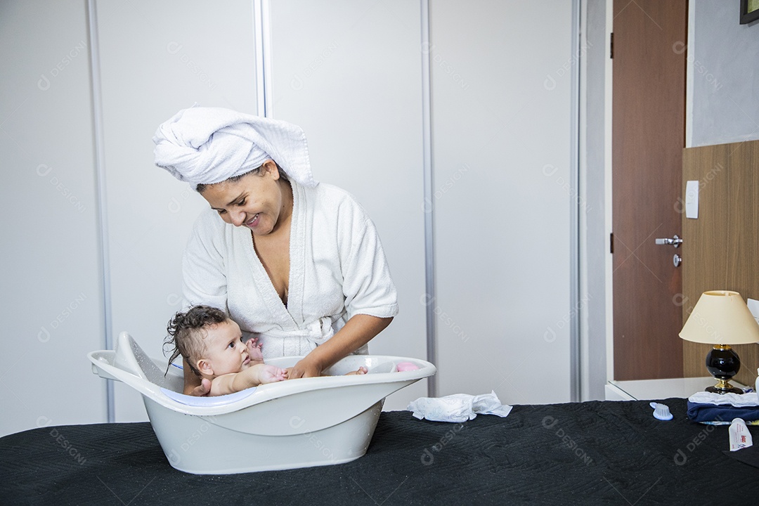 Mulher banhando seu bebê felizes