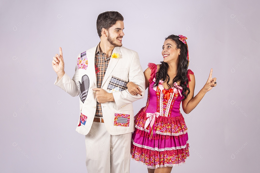 Casal de quadrilheiros trajados para festa junina apontando para o lado