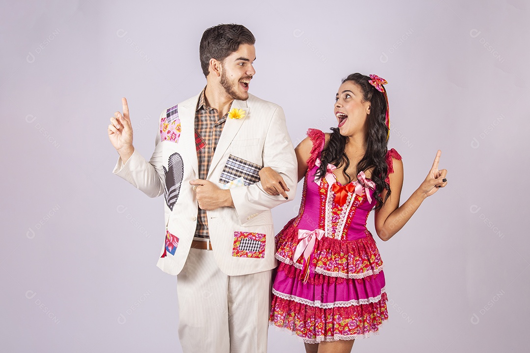 Casal de quadrilheiros trajados para festa junina apontando para o lado