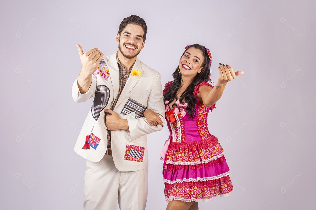 Casal de quadrilheiros trajados para festa junina com gesto chamando