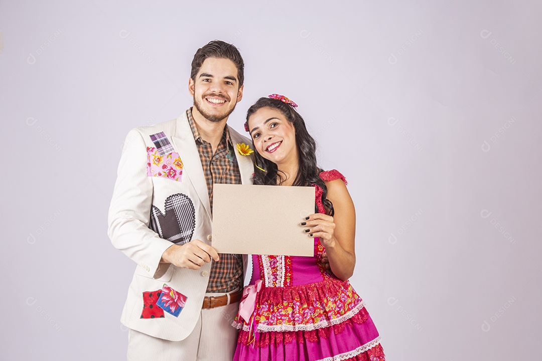 Casal de quadrilheiros trajados para festa junina segurando plaquinha