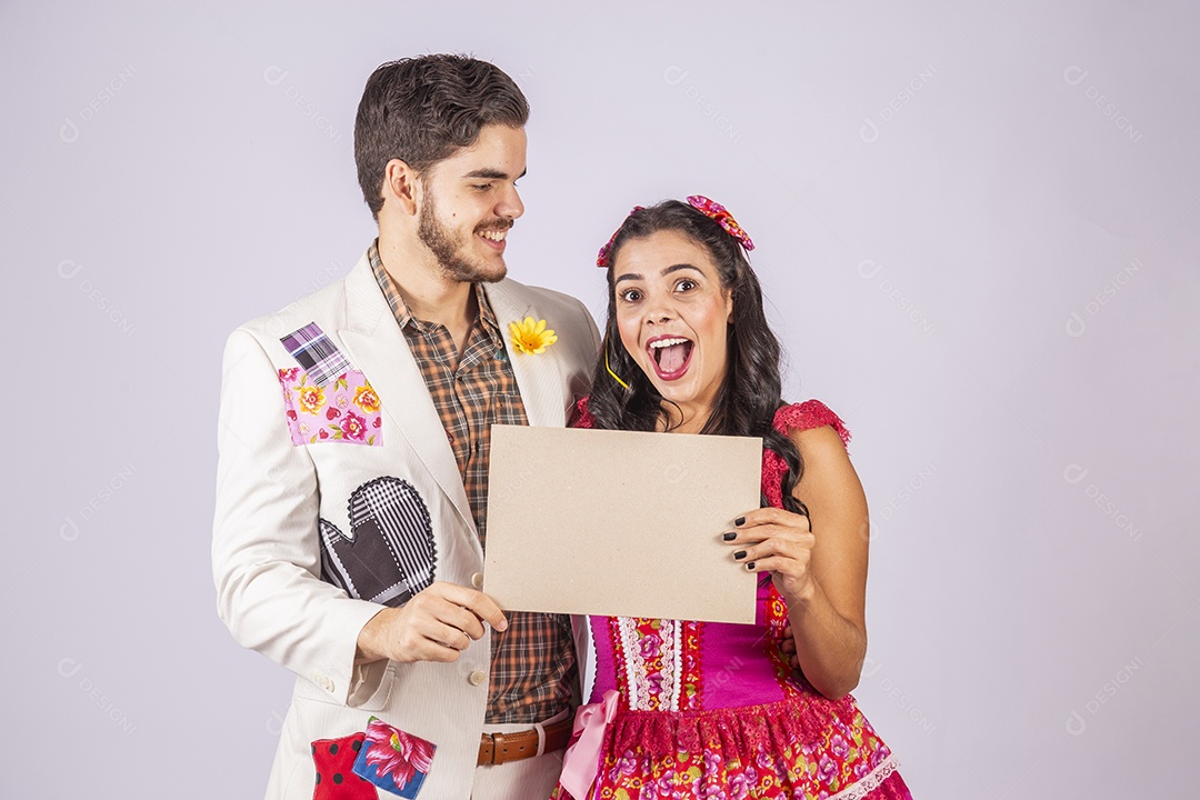 Casal de quadrilheiros trajados para festa junina segurando plaquinha