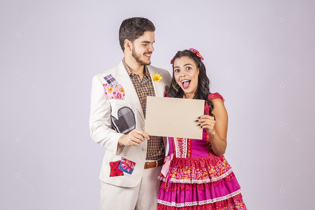 Casal de quadrilheiros trajados para festa junina segurando plaquinha