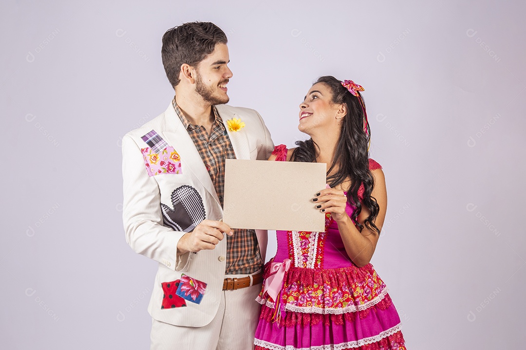 Casal de quadrilheiros trajados para festa junina segurando plaquinha