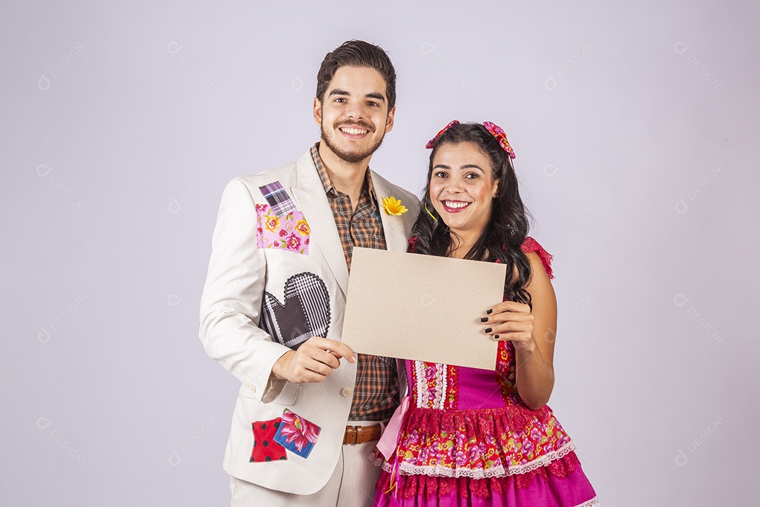 Casal de quadrilheiros trajados para festa junina segurando plaquinha