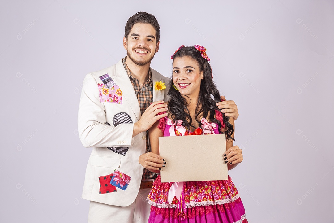 Casal de quadrilheiros trajados para festa junina segurando plaquinha