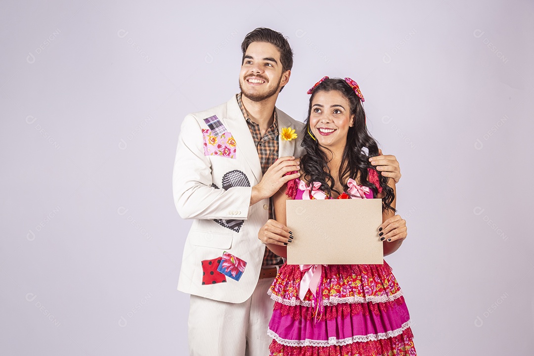 Casal de quadrilheiros trajados para festa junina segurando plaquinha