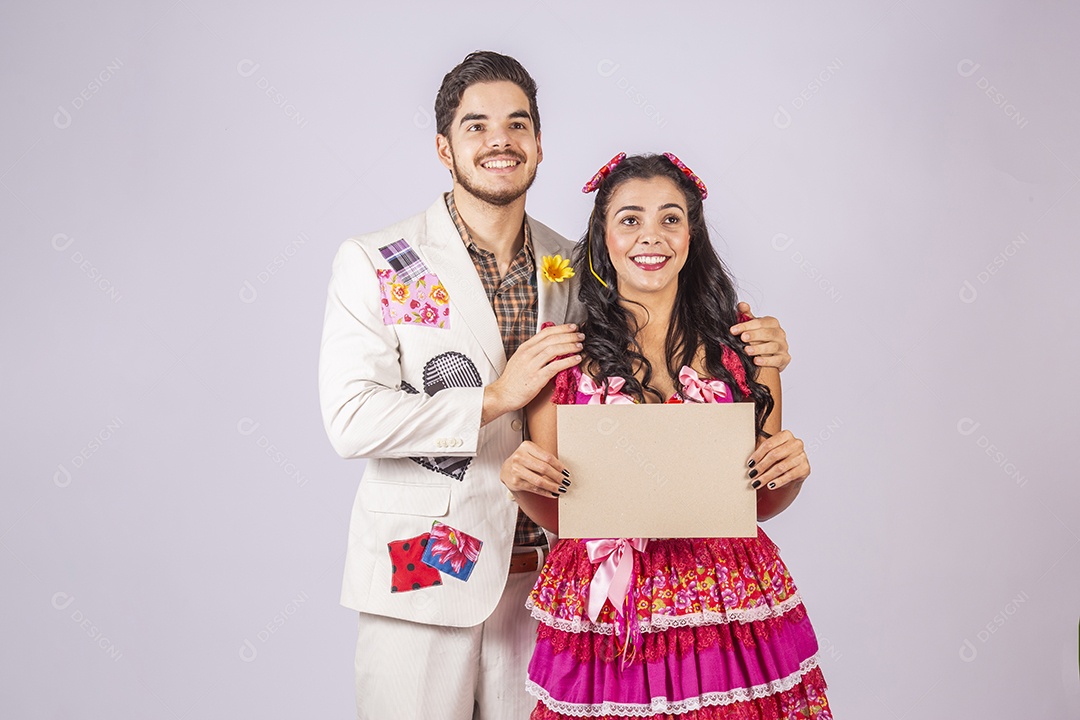 Casal de quadrilheiros trajados para festa junina segurando plaquinha