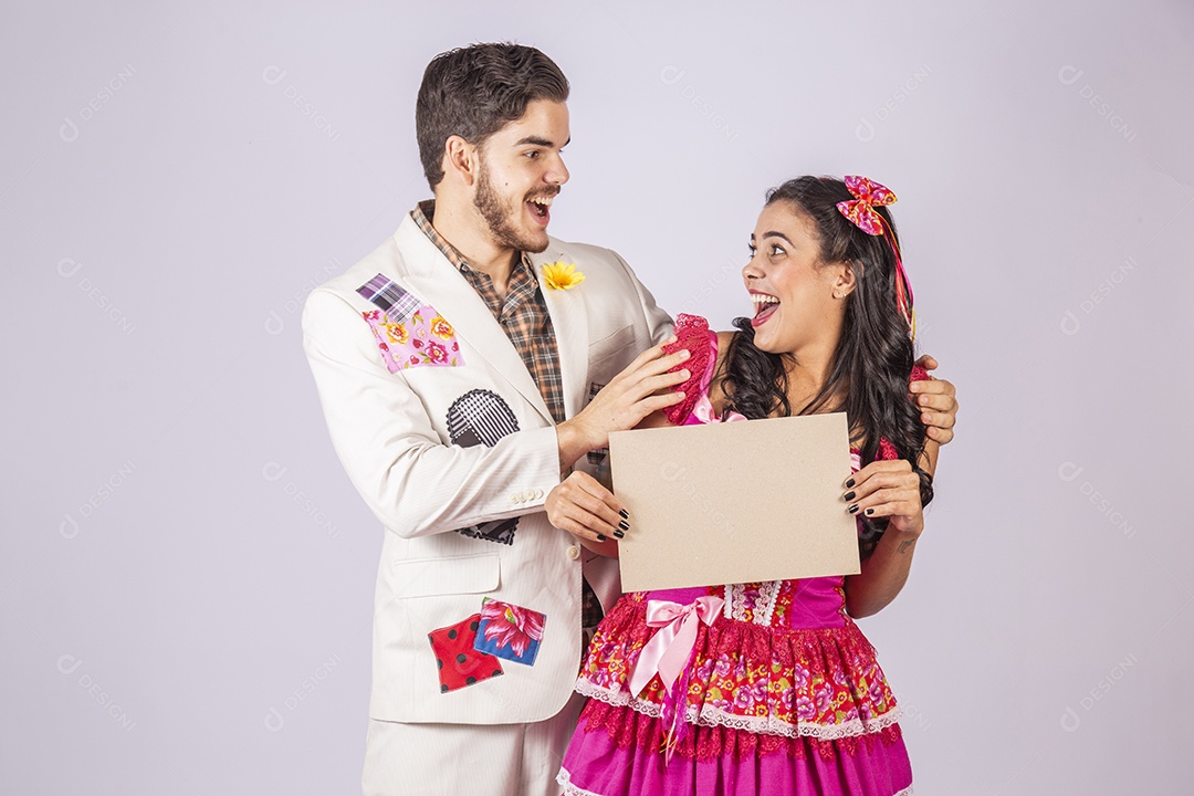 Casal de quadrilheiros trajados para festa junina segurando plaquinha