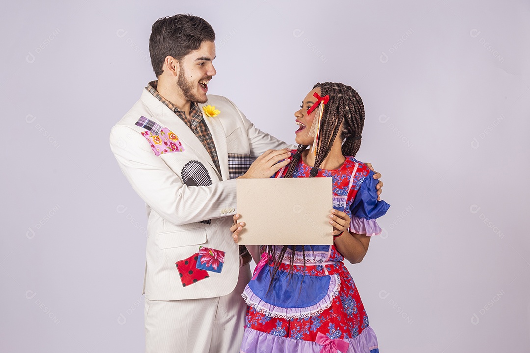 Casal de quadrilheiros trajados para festa junina segurando plaquinha